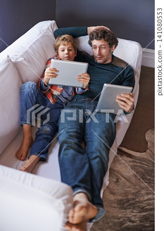 Father, son and tablet for gaming on sofa together, technology and online streaming for bonding at home. Digital world, internet and man with boy child in living room, gamer app and entertainment Father, son and tablet for gaming on sofa together, technology and online streaming for bonding at home. Digital world, internet and man with boy child in living room, gamer app and entertainment 141080553