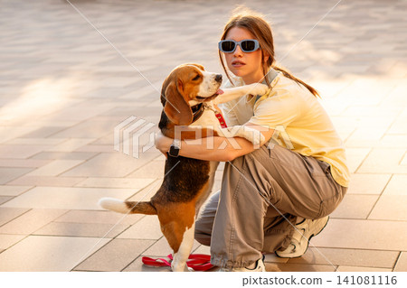 Beagle Hugging Young Woman During Outdoor Walk Beagle Hugging Young Woman During Outdoor Walk 141081116