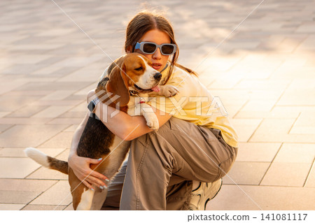 Young Woman Cuddling Happy Beagle Outdoors Young Woman Cuddling Happy Beagle Outdoors 141081117
