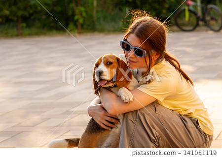 Young Woman Hugging Happy Beagle During Evening Walk Young Woman Hugging Happy Beagle During Evening Walk 141081119