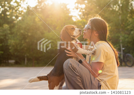 Young Woman Playing with Standing Beagle Outdoors Young Woman Playing with Standing Beagle Outdoors 141081123