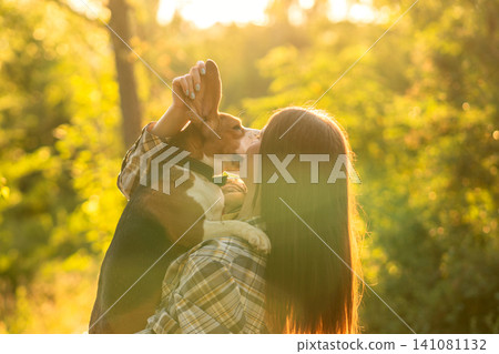 Woman Kissing Beagle During Golden Hour in Forest Woman Kissing Beagle During Golden Hour in Forest 141081132