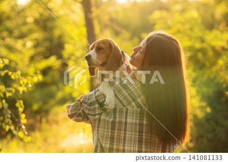 Woman Carrying Calm Beagle Outdoors at Sunset Woman Carrying Calm Beagle Outdoors at Sunset 141081133