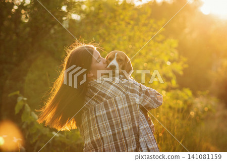 Woman Kissing Beagle During Golden Hour Walk Woman Kissing Beagle During Golden Hour Walk 141081159