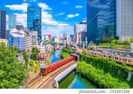 A rare sight in the urban landscape of Tokyo, Japan. The new Marunouchi Line 2000 series train and the river patrol boat "Chidori" appear side-by-side. Various other trains are also lined up. A rare sight in the urban landscape of Tokyo, Japan. The new Marunouchi Line 2000 series train and the river patrol boat "Chidori" appear side-by-side. Various other trains are also lined up. 141081266
