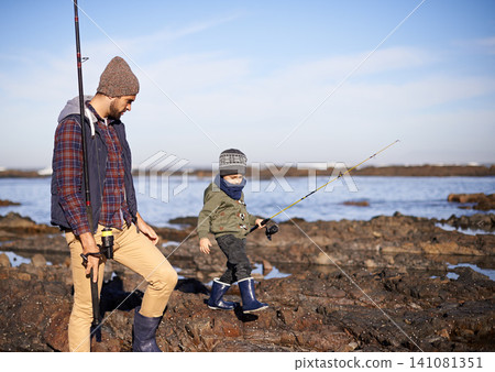 Man, kid and sea with fishing rod in winter for hobby, bonding and child development for growth and learn in Australia. Dad, boy and stand in boulders at coast for family tradition, memory and care 141081351