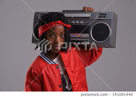 Child, hip hop and portrait with radio for cool music and dance in a studio with urban clothing. Fashion, African kid and boombox with trendy clothes and rap swag with confidence and grey background 141081440