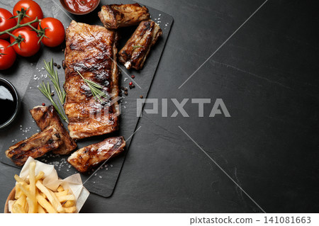 Delicious grilled ribs on black table, flat lay. Space for text 141081663