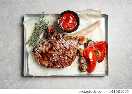 Delicious grilled ribeye with garnish on light table, top view 141081665
