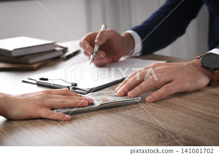 Woman giving bribe to man at table in office, closeup Woman giving bribe to man at table in office, closeup 141081702