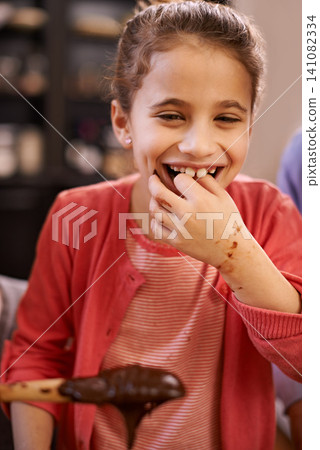 Portrait, baking and learning with girl, kid and child development with taste and ingredients. Face, home or recipe in a kitchen with snack or spoon with chocolate or food with fun, activity or hobby 141082334
