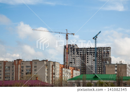 Urban construction site with cranes and residential buildings under blue sky Urban construction site with cranes and residential buildings under blue sky 141082345
