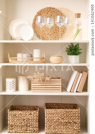 White shelving unit with dishware and different decorative stuff White shelving unit with dishware and different decorative stuff 141082400