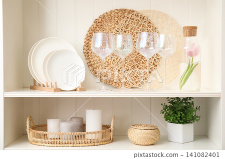 White shelving unit with glasses and different decorative stuff White shelving unit with glasses and different decorative stuff 141082401