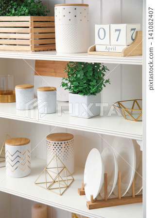 White shelving unit with dishes and different decorative stuff White shelving unit with dishes and different decorative stuff 141082407