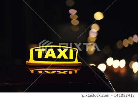 Taxi car with yellow roof sign on city street at night, closeup Taxi car with yellow roof sign on city street at night, closeup 141082412