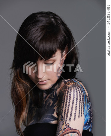 Creativity, ink and woman with tattoo in studio for creative design, trendy and body art with color. Female person, funky and edgy with artistic, blue and red for bold statement in gray background Creativity, ink and woman with tattoo in studio for creative design, trendy and body art with color. Female person, funky and edgy with artistic, blue and red for bold statement in gray background 141082493
