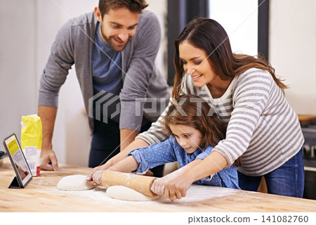 Cooking, pizza and family in kitchen with tablet for recipe, guide and mom and dad learning with child. Teaching, baking and girl helping parents with rolling pin in home and together for dinner Cooking, pizza and family in kitchen with tablet for recipe, guide and mom and dad learning with child. Teaching, baking and girl helping parents with rolling pin in home and together for dinner 141082760