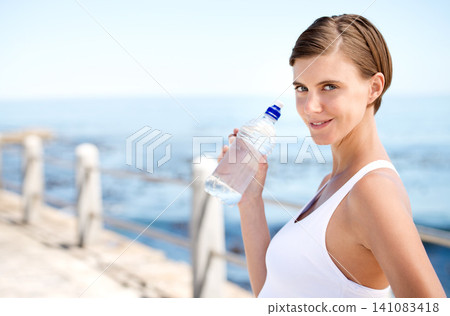 Woman, water bottle and outdoor at beach for health, fresh air and fitness in nature, h2o and sea. Nutrition, detox and liquid for thirst, hydration and exercise in portrait with drink for wellness Woman, water bottle and outdoor at beach for health, fresh air and fitness in nature, h2o and sea. Nutrition, detox and liquid for thirst, hydration and exercise in portrait with drink for wellness 141083418