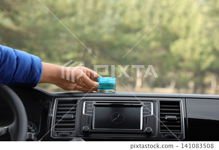 Man putting air freshener on dashboard in car, closeup. Space for text Man putting air freshener on dashboard in car, closeup. Space for text 141083508