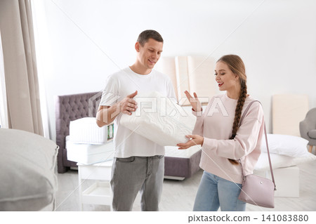 Happy couple choosing mattress in furniture store 141083880