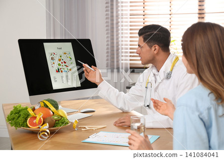 Nutritionist consulting patient at table in clinic Nutritionist consulting patient at table in clinic 141084041