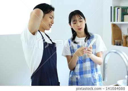 廚房:一對男女正在用智慧手機構思菜譜。 廚房:一對男女正在用智慧手機構思菜譜。 141084080
