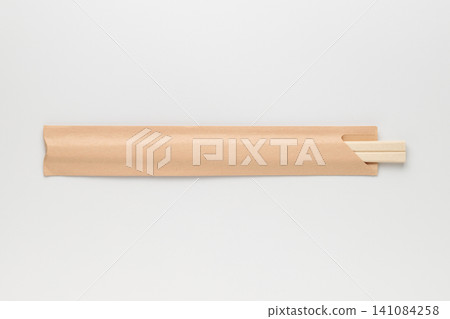Wooden chopsticks in a kraft paper bag placed against a white background. 141084258