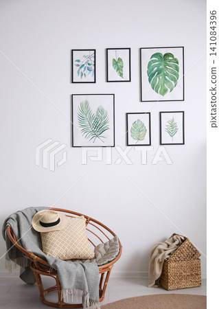 Beautiful paintings of tropical leaves on white wall in living room interior Beautiful paintings of tropical leaves on white wall in living room interior 141084396