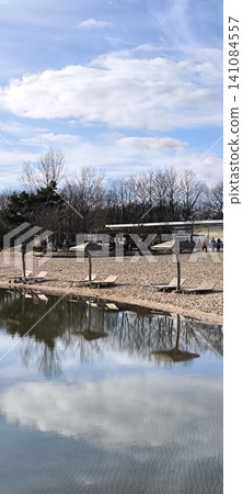 A sandy beach with straw umbrellas by the water on a winter day 141084557
