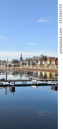 City pier for boats, yachts, sailboats. Blue sky and mirror-like surface of the lake City pier for boats, yachts, sailboats. Blue sky and mirror-like surface of the lake 141084559