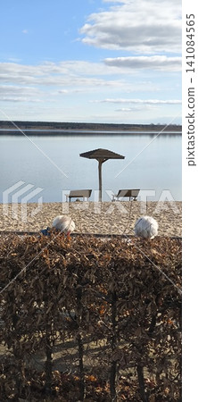 Rear view of an elderly couple relaxing on a lakeside promenade on a sunny day. Rear view of an elderly couple relaxing on a lakeside promenade on a sunny day. 141084565