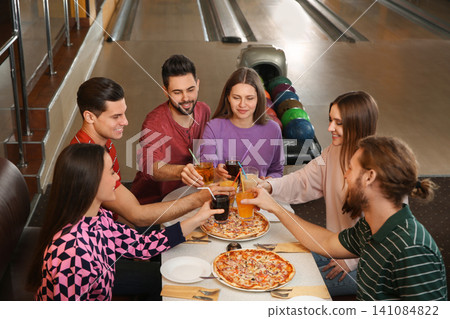 Group of friends with drinks and pizza in bowling club Group of friends with drinks and pizza in bowling club 141084822