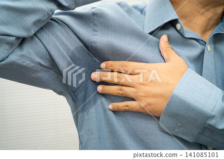 Man with sweaty arm pit on shirt when working in office, Hyperhidrosis sweating. Man with sweaty arm pit on shirt when working in office, Hyperhidrosis sweating. 141085101