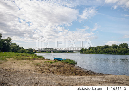 peaceful riverbank scene with boat and bridge in rural landscape photography periodical editorial resource for travel imagery and nature scenes design and visual story. peaceful riverbank scene with boat and bridge in rural landscape photography periodical editorial resource for travel imagery and nature scenes design and visual story. 141085240