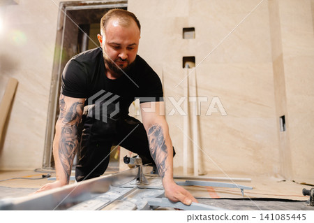 Tiler cutting tile with manual cutter in bathroom Tiler cutting tile with manual cutter in bathroom 141085445