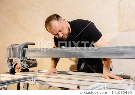 Construction worker using tile saw cutting machine preparing ceramic tiles for bathroom renovation Construction worker using tile saw cutting machine preparing ceramic tiles for bathroom renovation 141085450