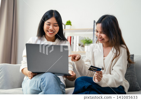 Two young Asian women used a laptop computer to shopping online and paid by credit card. Two young Asian women used a laptop computer to shopping online and paid by credit card. 141085633