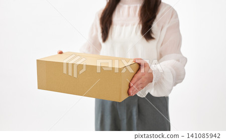 A woman in her 20s holding a cardboard box. A woman in her 20s holding a cardboard box. 141085942