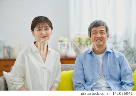 A senior couple relaxing on a sofa, smiling. A senior couple relaxing on a sofa, smiling. 141086041