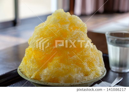 A generously sized mango shaved ice placed on a table in a Japanese-style room. A generously sized mango shaved ice placed on a table in a Japanese-style room. 141086217