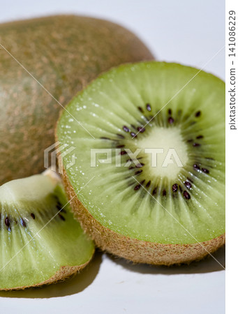 Fresh kiwi fruit half and cut slice close-up on white background. Fresh kiwi fruit half and cut slice close-up on white background. 141086229
