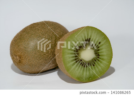 Whole kiwi fruit and a cut half isolated on a white background. Whole kiwi fruit and a cut half isolated on a white background. 141086265