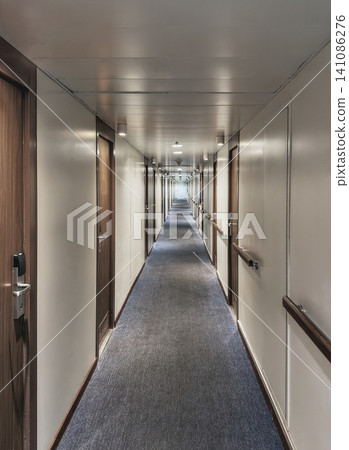 Long narrow corridor inside a cruise ship or hotel with wooden doors. Long narrow corridor inside a cruise ship or hotel with wooden doors. 141086276