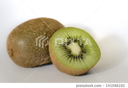 Whole kiwi fruit next to a fresh cut half on white background. Whole kiwi fruit next to a fresh cut half on white background. 141086282