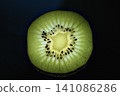 Backlit kiwi fruit slice glowing against a dark background. 141086286