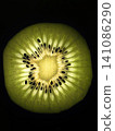 Glowing kiwi slice close-up on black background. 141086290