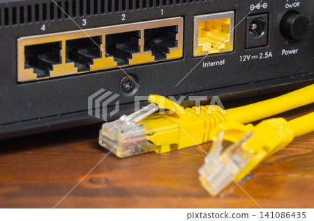Yellow ethernet cable connected to a network router port close up. Yellow ethernet cable connected to a network router port close up. 141086435