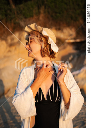 Young woman scratching neck feeling irritation on beach at sunset Young woman scratching neck feeling irritation on beach at sunset 141086456