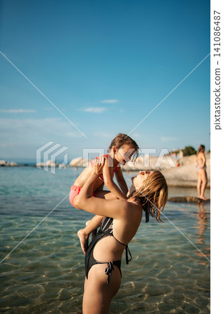 Mother and daughter bonding playing in ocean water during vacation 141086487